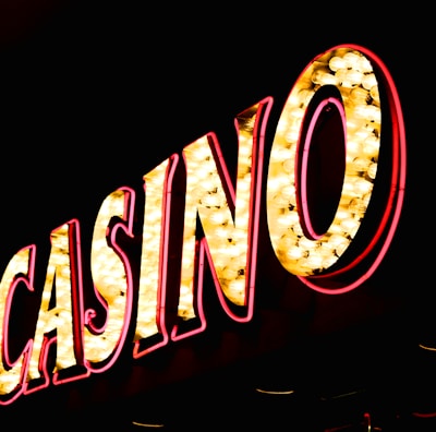 Brightly illuminated letters spell out 'CASINO' with glowing yellow bulbs and red outlines against a dark background.